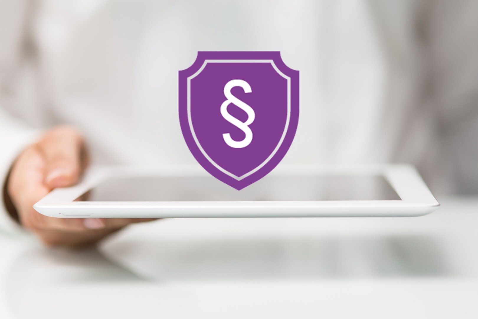 Tablet mit Schutzschild und Paragraph-Zeichen als Symbol für IT-Compliance, Datenschutz und rechtssichere digitale Prozesse im B2B.