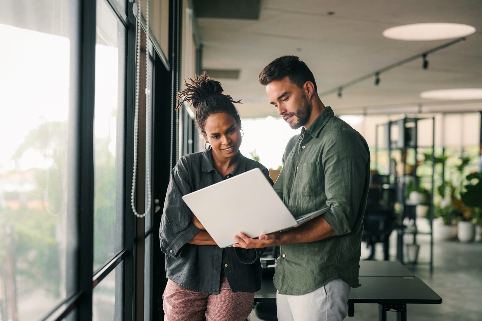 Zwei Kollegen besprechen am Laptop im modernen Büro nächste Schritte – Zusammenarbeit, Anforderungsanalyse und Projektabstimmung im B2B-IT-Umfeld.