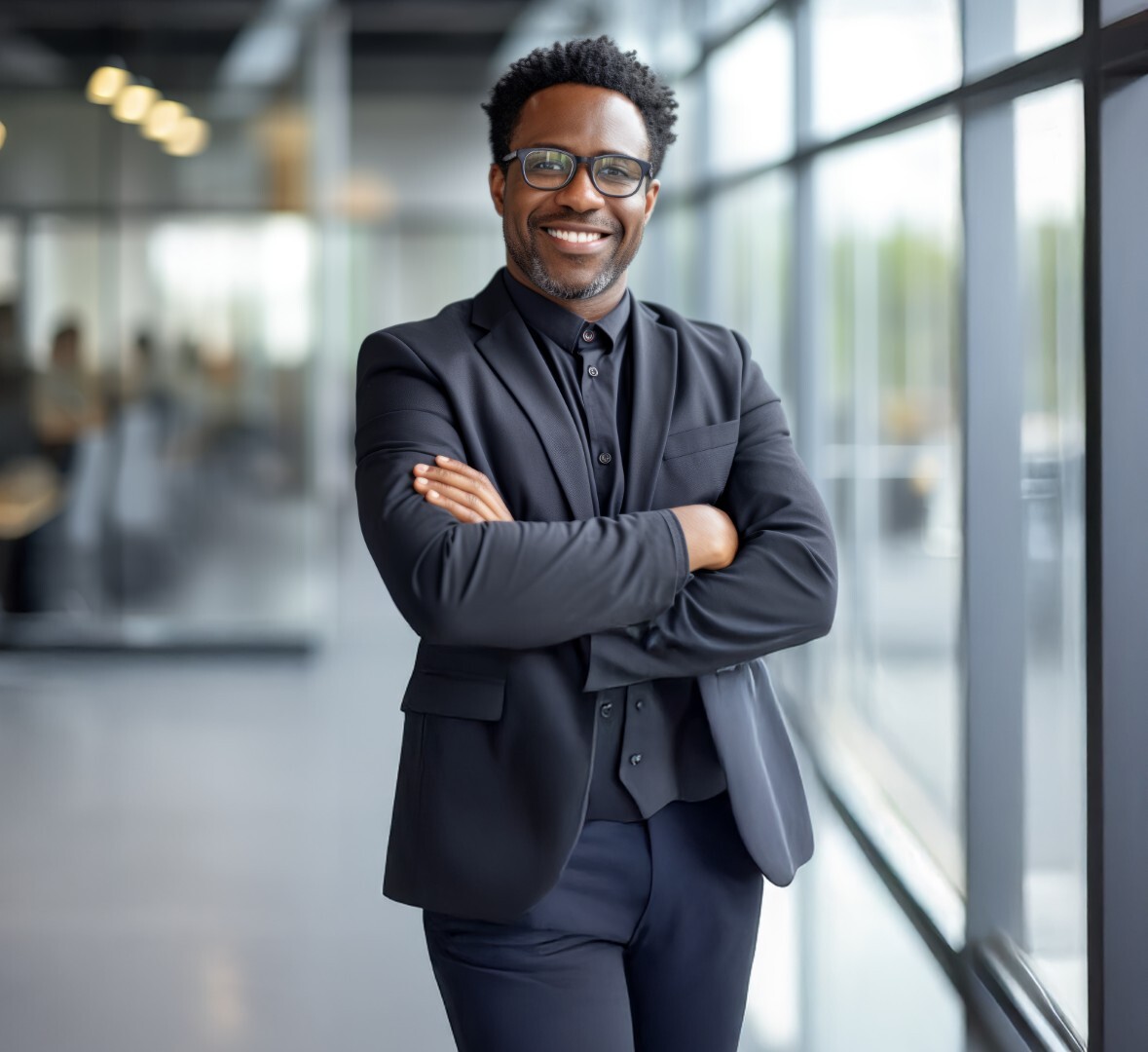 Business-Porträt: IT-Manager im Anzug mit verschränkten Armen in modernem Bürogebäude, steht für Beratung und Leadership